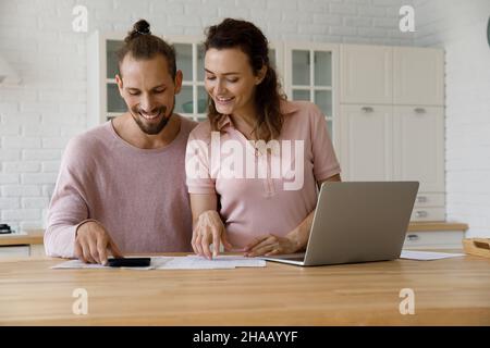 Coppia felice di inquilini che fanno i documenti domestici in cucina Foto Stock
