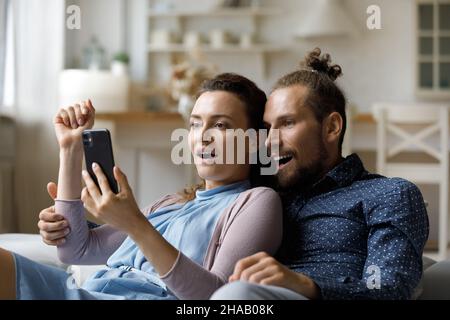 Eccitato sorpreso coppia di incontri millennial ottenere notizie inaspettate su smartphone Foto Stock