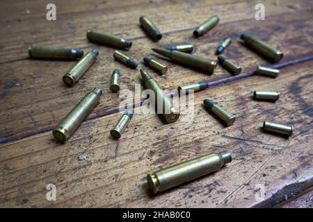 Colpo angolato di proiettili e conchiglie vuote su un tavolo di legno Foto Stock