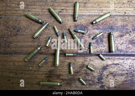 Proiettili e conchiglie vuote su un tavolo di legno Foto Stock