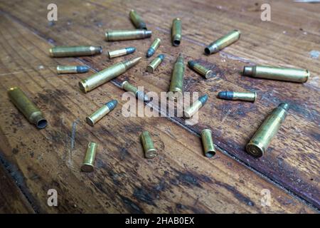 Colpo angolato di proiettili e conchiglie vuote su un tavolo di legno Foto Stock