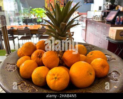 Ananas maturo circondato da arance. Still-life su sfondo blu in legno. Foto Stock