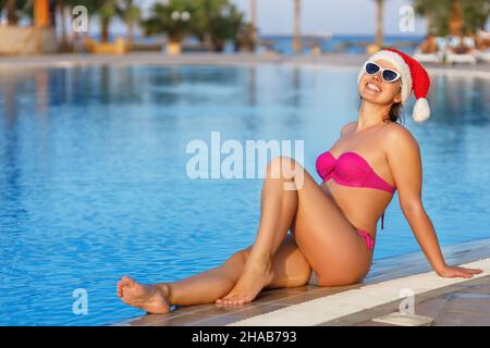 giovane donna sorridente a santa hat in piscina Foto Stock