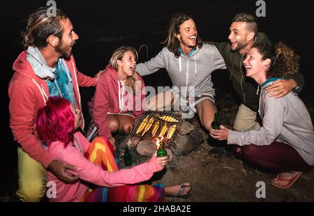 Giovani amici indipendenti che si divertono insieme a notte Beach party cucinare pannocchie al fuoco - concetto di viaggio amicizia con persone alternative viaggiatori Foto Stock