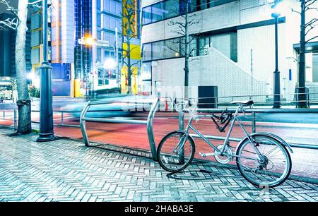 Scena notturna con bicicletta parcheggiata e auto a velocità sfocata nel centro della città di Tokyo capitale del Giappone - Urban Travel Concept Foto Stock