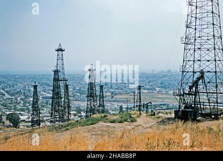 Oilwells a Signal Hill, Long Beach, California, USA nel giugno 1954 – questa vista mostra quanto vicino il campo petrolifero è urbano Los Angeles e l'Oceano Pacifico oltre. Si possono vedere derrick in legno e acciaio, oltre a uno o due “asini annuenti” (pompjack) e serbatoi di stoccaggio. Il Long Beach Oil Field è stato scoperto nel 1921. Il periodo di massimo splendore del campo è stato il 1920s, con centinaia di derrick petroliferi che coprono Signal Hill e le parti adiacenti di Long Beach. Il campo è ormai in gran parte esaurito – una fotografia d'epoca del 1950s. Foto Stock