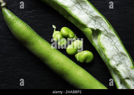 Fotografia di un baccello di fagiolo chiuso e aperto e di quattro fagioli isolati su sfondo ardesia per illustrazioni alimentari Foto Stock