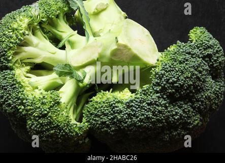 Fotografia di due mazzi di broccoli su sfondo ardesia per illustrazioni alimentari Foto Stock