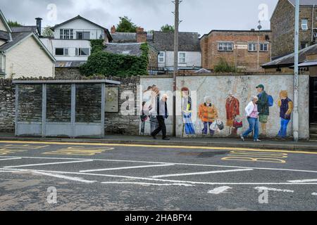 Una fermata dell'autobus con un murale raffigurante la gente locale in attesa di un autobus, Builth Wells, Powys, Galles Foto Stock