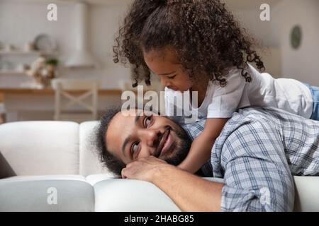 La figlia che si trova sul dorso del papà può godersi il tempo insieme a casa Foto Stock