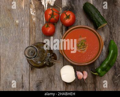 Ciotola di gazpacho su tavola di legno. Ingredienti per la cottura della zuppa di pomodoro andalusa, vista dall'alto Foto Stock