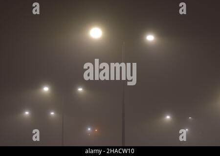 Nebbia in città in serata illuminata da lampioni. Notte. Foto Stock