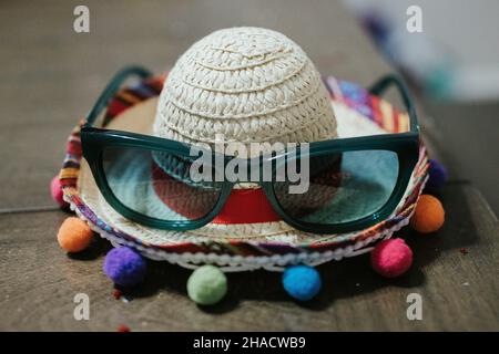 Un paio di occhiali da sole verdi su un divertente cappello colorato su una superficie di legno Foto Stock