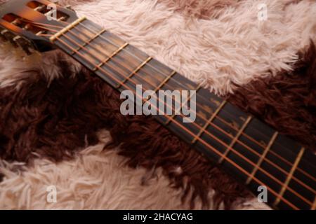 Chitarra usata con filo metallico rotto su un tappeto Foto Stock