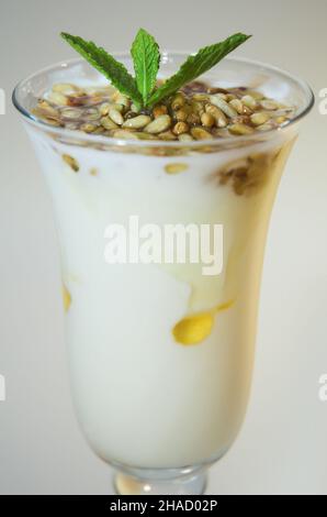 Yogurt con miele e pinoli in vetro chiaro su sfondo bianco Foto Stock