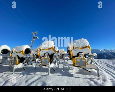 Golm, Austria, 12.12.2021. Molti cannoni gialli di neve parcheggiati nella stazione sciistica contro il cielo blu. Foto Stock