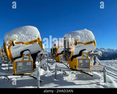 Golm, Austria, 12.12.2021. Gruppo di cannoni gialli di neve parcheggiati nella stazione sciistica contro il cielo blu. Foto Stock