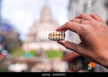 Mano che tiene un biscotto francese del macaroon, Macaron, sulla strada di Parigi Foto Stock