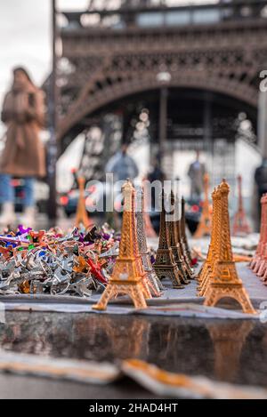 Souvenir della torre Eiffel con una vera torre Eiffel sullo sfondo. Foto Stock