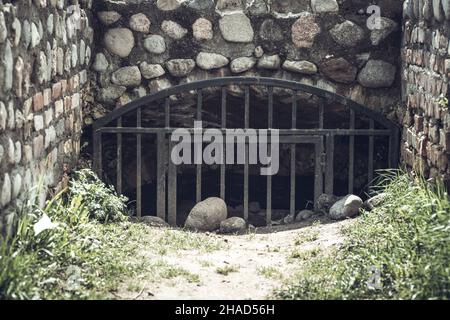 Ingresso ad un bunker sotterraneo in cemento abbandonato segreto dai tempi dell'URSS. L'ingresso è chiuso da un forte grill in metallo. Foto Stock