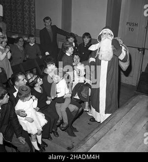 1965, storica, in una sala del villaggio, un babbo natale spaventoso, bambine tenute dai loro genitori spaventato da a babbo natale con una maschera facciale e falsa barba, Fife, Scozia, UK Foto Stock