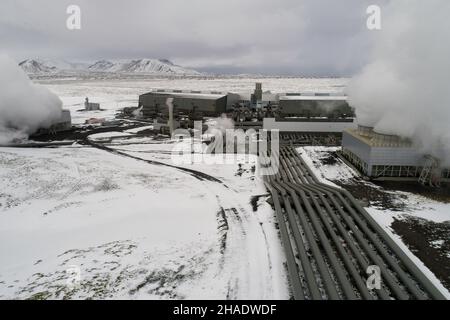 Tubazioni complesse in una centrale geotermica sparate con un drone in inverno con la neve a terra Foto Stock