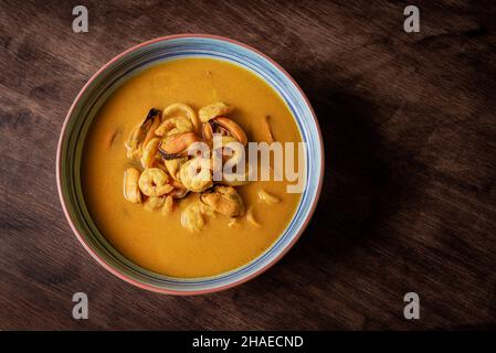 Zuppa di pesce a base di gamberi, cozze, vongole, naselli e calamari, su un tavolo di legno scuro. Vista Nadir. Foto Stock