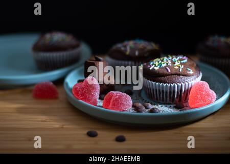 Delizioso cupcake di muffin al cioccolato con coloratissimi spruzzi di topin bianco crema, tartufi e caramelle a forma di cuore per la festa di San Valentino per l'amore Foto Stock