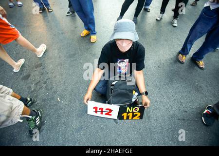 Bangkok, Tailandia. 12th Dic 2021. Un manifestante siede a terra mentre tiene i cartelli durante la dimostrazione. I manifestanti chiedono le dimissioni del primo Ministro Prayuth Chan-ocha e l'abolizione della legge Lese-Majeste del 112. Credit: SOPA Images Limited/Alamy Live News Foto Stock