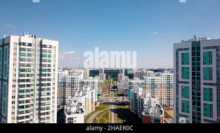 Vista aerea di un grande quartiere cittadino con strade soleggiate e alti edifici residenziali su sfondo cielo blu. Video. Bella zona colorata della città, Foto Stock