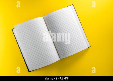 Notebook con fodera aperta isolato su sfondo giallo nella vista dall'alto, disposizione piatta, spazio di copia, percorso di ritaglio Foto Stock