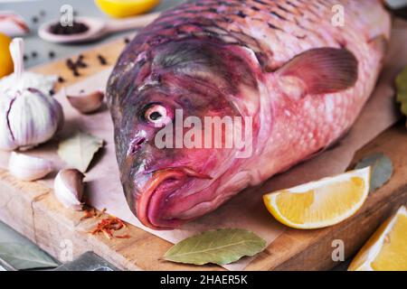 Carpa di pesce di fiume sul tagliere con ingredienti per la cottura Foto Stock