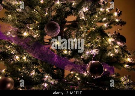 Primo piano di albero di Natale decorato, palle ornamento d'argento e viola scintillante garland nastro Foto Stock