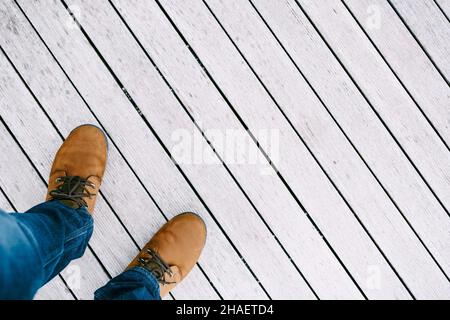 I piedi maschi in scarpe marroni poggiano su un pavimento di legno bianco. Primo piano Foto Stock
