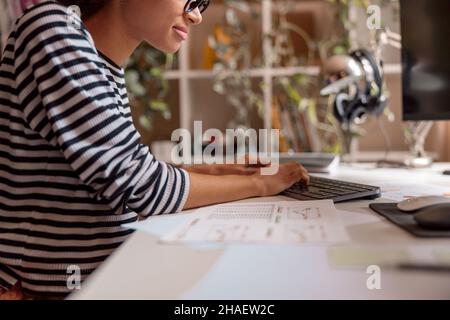 Giovane donna che usa il computer desktop a casa Foto Stock