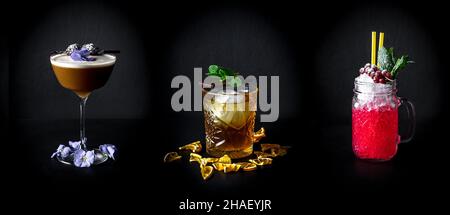 Una collezione di tre cocktail in diversi tipi di bicchieri isolati su sfondo nero Foto Stock