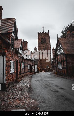 Chiesa strada in un giorno d'autunno cupo in un piccolo villaggio a Cheshire. Great Budworth, Cheshire, Inghilterra Regno Unito. Foto Stock