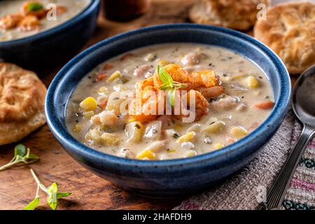 Una ciotola di deliziosi gamberi fatti in casa e zuppa di mais con biscotti su un rustico tavolo di legno. Foto Stock