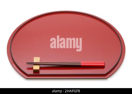 Bacchette in legno su vassoio laccato rosso con supporto per bacchette, isolate su sfondo bianco Foto Stock