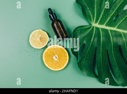 Grandi foglie verdi, rullo per massaggio facciale su sfondo verde. Tropic foglia di palma in primo piano con gocce d'acqua. Modello estivo, piatto. Cosmetologia Foto Stock
