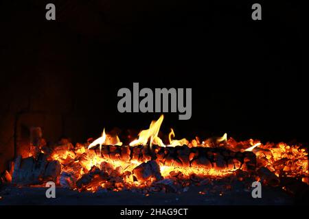 Scintille calde rosse che bruciano volano dal fuoco grande. Bel sfondo astratto sul tema del fuoco. Carboni brucianti, particelle infiammate che volano contro la colpa Foto Stock