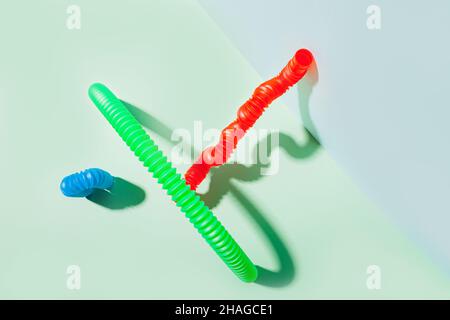 Il tubo pop curvo è appoggiato contro la parete. Vita morta moderna con giocattolo antistress. Foto Stock