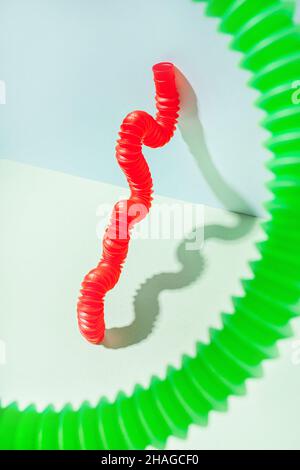 Il tubo curvo è appoggiato contro la parete con la messa a fuoco sullo sfondo. Vita morta moderna con giocattolo antistress. Foto Stock