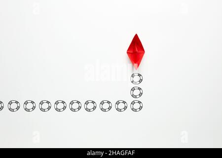 Origami carta rossa barca si muove con lasciare le tracce di vita boe. Sostegno, aiuto, assicurazione, assistenza alle imprese, orientamento, leadership o salvataggio conce Foto Stock