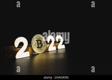 Bitcoin 2022. Singola moneta d'oro Bitcoin accanto ai numeri su sfondo nero con spazio per la copia. Prezzo, valore futuro del concetto di previsione criptato BTC. Foto Stock