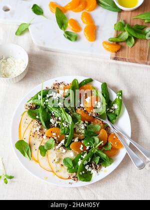 Insalata di spinaci e quinoa con pere, arance e ricotta. Preparazione pasto sano. Piatti a base di piante. Vita verde. Ricetta vegana. Styling alimentare. Vegetariano Foto Stock