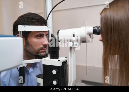 L'optometristo che brilla nell'occhio del paziente con la lampada a fessura Foto Stock