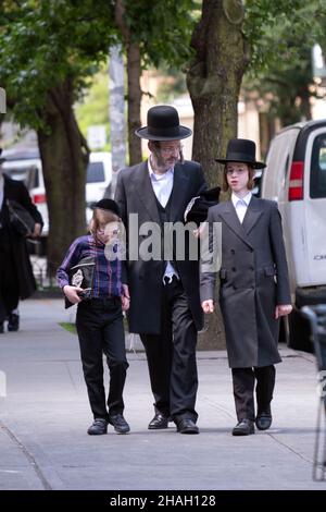 Un padre ebreo ortodosso e un figlio ritornano dalla sinagoga al mattino e camminano insieme su Lee Ave. A Williamsburg, Brooklyn, New York City. Foto Stock