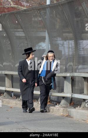 AMICI. I ragazzi ebrei ortodossi con un lungo peyot riccio attraversano un ponte sul BQE e condividono una risata. A Williamsburg, Brooklyn, New York. Foto Stock