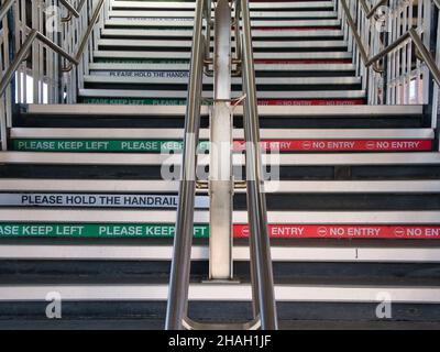 Presso la stazione ferroviaria di York nello Yorkshire, Regno Unito, una serie di scale con corrimano in acciaio da una piattaforma. L'insegna chiede ai viaggiatori di tenere la sinistra e non di camminare Foto Stock